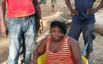 A differently-abled lady being transported in a wheelbarrow to receive a wheelchair from Senator Kupee